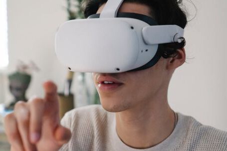 Virtual Reality And Augmented Reality - Young male interacting with virtual reality headset in apartment