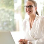 Career - Laughing businesswoman working in office with laptop