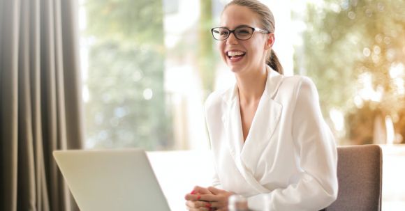 Career - Laughing businesswoman working in office with laptop