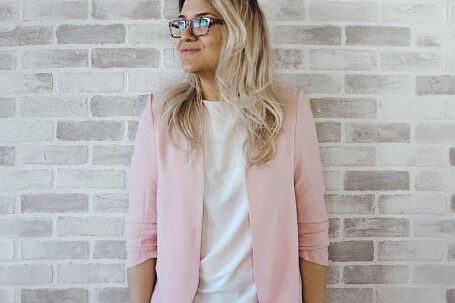 Career - Woman in Pink Cardigan and White Shirt Leaning on the Wall