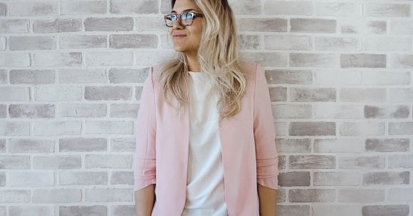 Career - Woman in Pink Cardigan and White Shirt Leaning on the Wall