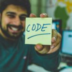 Coding - Man In Grey Sweater Holding Yellow Sticky Note