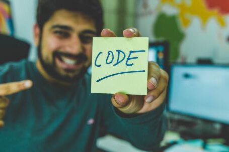 Coding - Man In Grey Sweater Holding Yellow Sticky Note