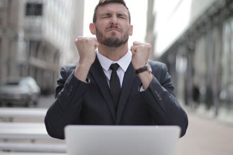 Career - Man in Black Suit Sitting on Chair Beside Buildings