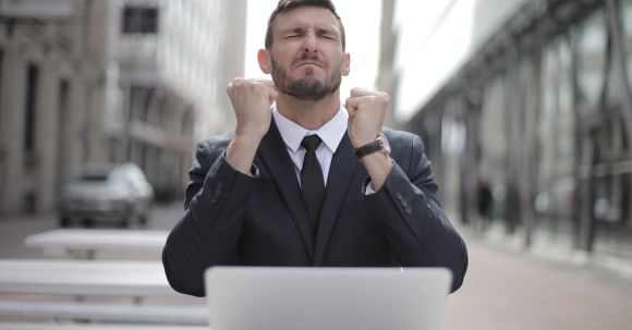 Career - Man in Black Suit Sitting on Chair Beside Buildings