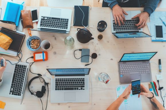 Technology - people sitting down near table with assorted laptop computers