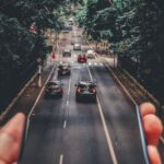 Mobile App - Forced Perspective Photography of Cars Running on Road Below Smartphone