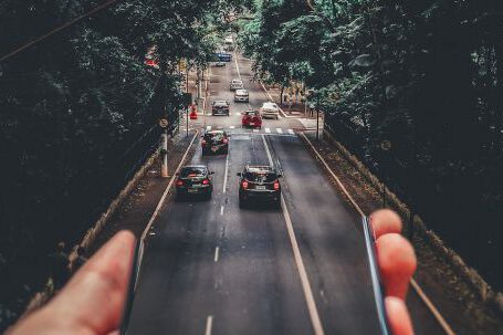 Mobile App - Forced Perspective Photography of Cars Running on Road Below Smartphone