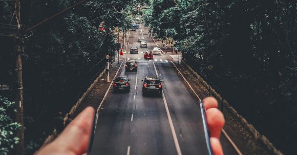 Mobile App - Forced Perspective Photography of Cars Running on Road Below Smartphone