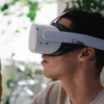 Virtual Reality And Augmented Reality - Side view of concentrated young guy in casual clothes experiencing virtual reality in modern headset at home