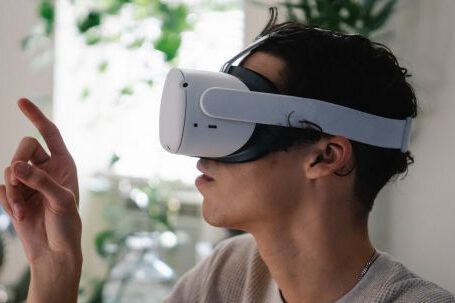 Virtual Reality And Augmented Reality - Side view of concentrated young guy in casual clothes experiencing virtual reality in modern headset at home