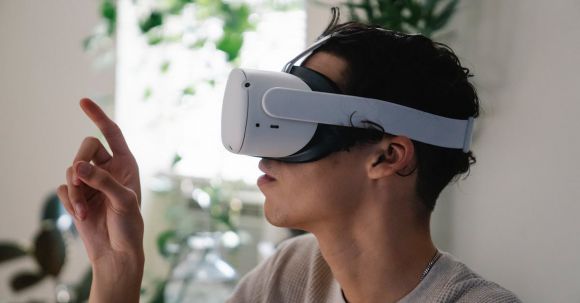 Virtual Reality And Augmented Reality - Side view of concentrated young guy in casual clothes experiencing virtual reality in modern headset at home