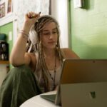 Laptop - a woman with dreadlocks sitting in front of a laptop computer