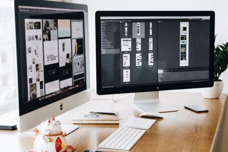 Web Design - Two Imac's With Keyboard and Phones on Desk