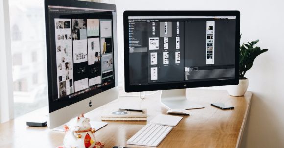 Web Design - Two Imac's With Keyboard and Phones on Desk