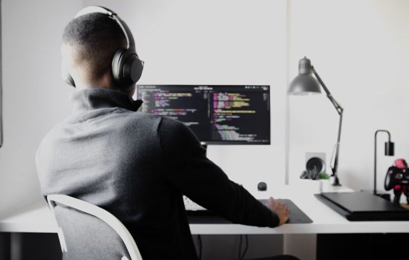 Debugging - man in black long sleeve shirt wearing black headphones sitting on chair