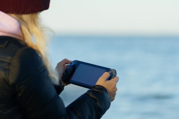 Pc - a woman holding a game controller in front of a body of water